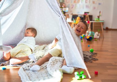 Anaokulunda bir sürü oyuncağın etrafında oynayan sevimli sarışın ikizler.