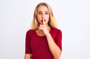 İzole edilmiş beyaz arka planda kırmızı tişört giyen genç ve güzel bir kadın sessiz olmak istiyor. Sessizlik ve gizli konsept.