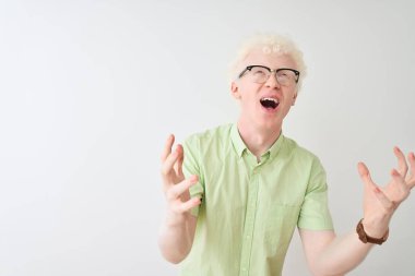 Yeşil tişörtlü, gözlüklü genç sarışın adam izole edilmiş beyaz arka planda deli deli deli bağırıyor ve agresif bir ifade ve kollarla bağırıyor. Hayal kırıklığı konsepti.