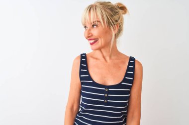 Normal çizgili tişört giyen orta yaşlı bir kadın izole edilmiş beyaz arka planda dikilip yüzünde gülümseme, doğal bir ifade ile yan yana bakıyor. Kendinden emin gülen.