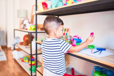 Güzel çocuk anaokulunda ahşap bloklarla oynuyor.