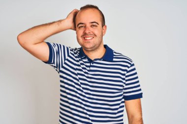 Sıradan çizgili polo giyen genç adam izole edilmiş beyaz arka planda duruyor. Kendine güvenen, el hareketleriyle saçlara dokunan, çekici ve modaya uygun poz veren biri.