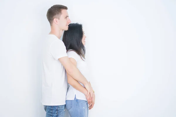 若い美しいカジュアルなTシャツを身に着けているカップルは 横に探して隔離された白い背景の上に立っています 自信を持って笑顔で自然な顔でプロファイルポーズをリラックス — ストック写真