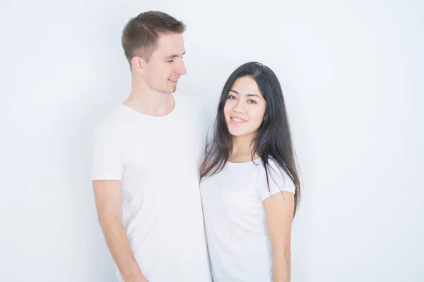 カジュアルなTシャツを着た若い美しいカップルは 顔に幸せでクールな笑顔で孤立した白い背景の上に立っています ラッキーな人 — ストック写真