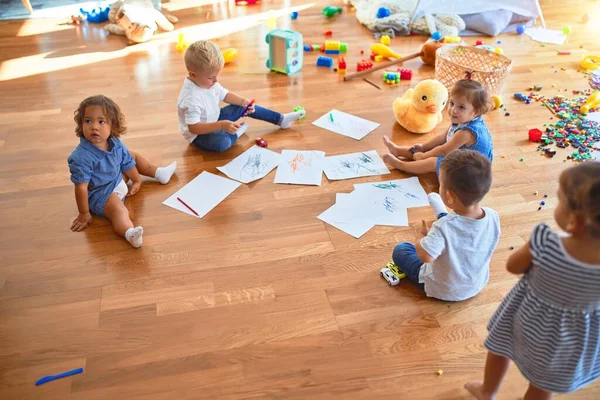 幼儿园里 一群可爱的幼儿坐在地板上 用纸笔画着许多玩具 — 图库照片