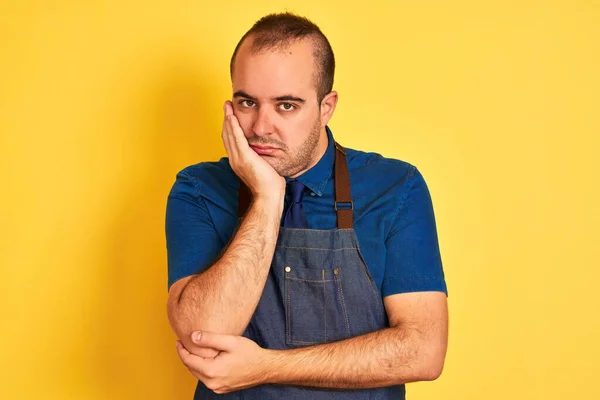 Young Shopkeeper Man Wearing Apron Standing Isolated Yellow Background Thinking — 스톡 사진