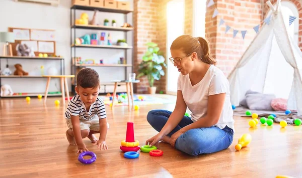 Hermosa Maestra Niño Pequeño Construyendo Pirámide Con Aros Bolcks Jardín — Foto de Stock