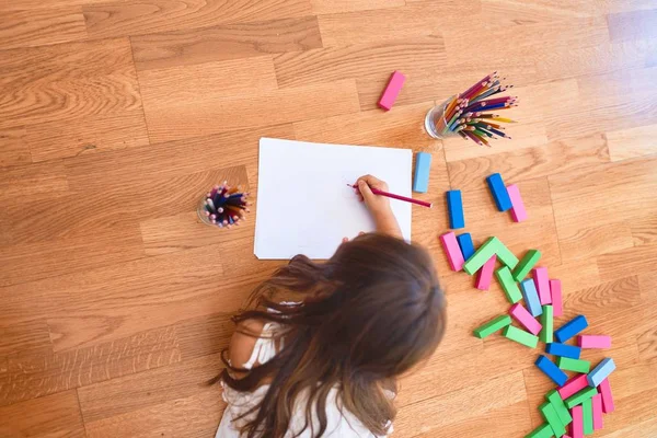 Adorable toddler lying down on the floor drawing using paper and pencils at kindergarten — Stock Image Adorable Toddler Lying Floor Drawing Using Paper Pencils Kindergarten Stock Image