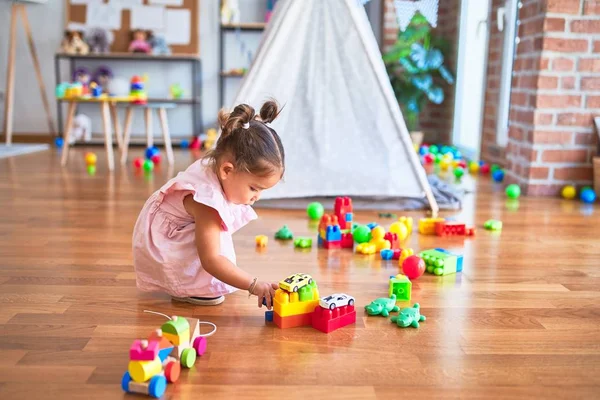 Young beautiful toddler sitting on the floor playing with small cars toys at kindergaten — Stock Image Young Beautiful Toddler Sitting Floor Playing Small Cars Toys Kindergaten Stock Image