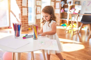 Sevimli sarışın çocuk anaokulunda bir sürü oyuncakla oynuyor.