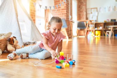 Güzel sarışın küçük kız anaokulunda trenle oynuyor.