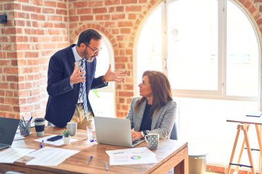 Two middle age business workers working together. Man bullying woman at the office clipart