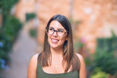 Mutlu ve kendinden emin gülümseyen genç ve güzel bir kadın. Kasaba caddesinde yüzünde gülümsemeyle dikilirken