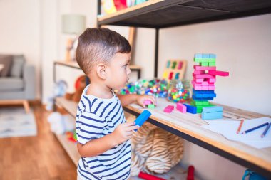 Güzel çocuk anaokulunda ahşap bloklarla oynuyor.