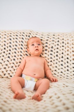 Evdeki battaniyenin üzerinde kanepeye uzanmış sevimli bir bebek. Yeni doğmuş bebek rahatlıyor ve dinleniyor.