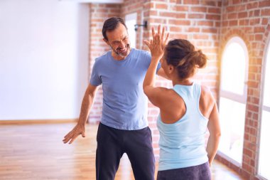 Middle age beautiful sporty couple smiling happy. Standing with smile on face highing five at gym clipart