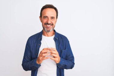 İzole edilmiş beyaz arka plan üzerinde duran mavi kot gömlek giyen orta yaşlı yakışıklı adam ellerini birleştirip gülümseyerek gevşemiş ve neşeli olmasını diliyordu. Başarı ve iyimser