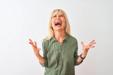 Yalıtılmış beyaz arka planda duran yeşil tişörtlü, çılgın ve sinirli bir kadın agresif bir ifadeyle bağırıyor ve kollarını kaldırıyor. Hayal kırıklığı konsepti.