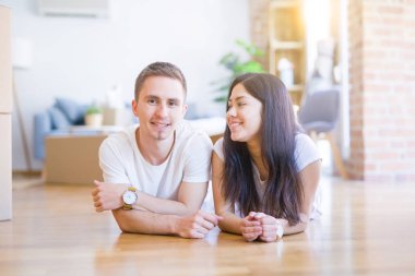 Genç güzel çift karton kutular etrafında yeni evde yatarken