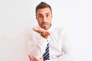 Genç yakışıklı, zarif bir iş adamı, izole edilmiş arka planda kameraya bakıyor ve havada bir öpücük savuruyor. Güzel ve seksi. Aşk ifadesi.