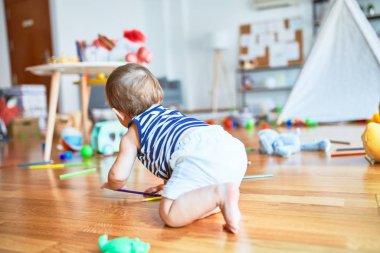 Anaokulunda bir sürü oyuncakla oynayan sevimli bir çocuk.