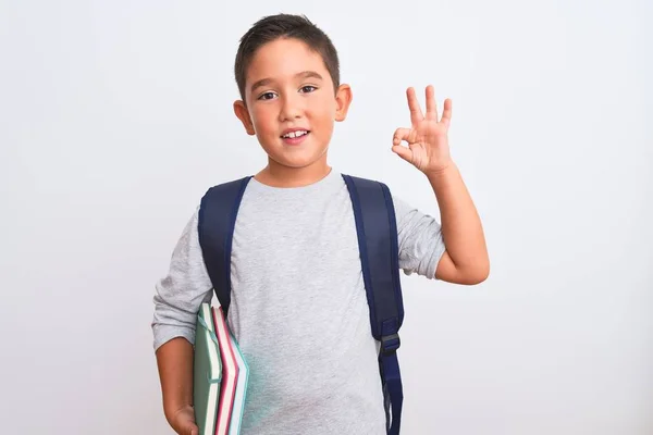 美しい学生の子供の男の子を身に着けているバックパックを保持本上の隔離された白い背景を持っている指でOkサインを行う 優れたシンボル — ストック写真