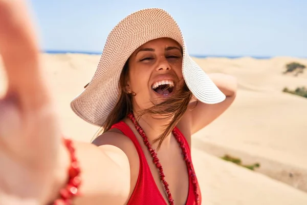 若いです美しいです女性日光浴夏の水着を身に着けています自画撮り使用してスマートフォンでMaspalomas Dules Bech — ストック写真