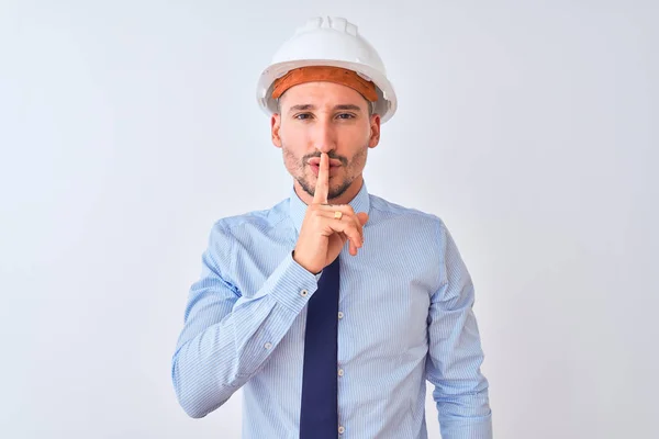 年轻的商人戴着承包商安全帽 在孤立的背景下要求保持安静 手指放在嘴唇上 沉默和秘密概念 — 图库照片