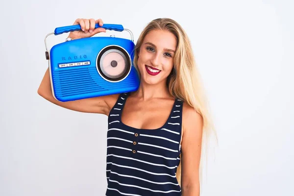 Young beautiful woman holding vintage radio standing over isolated white background with a happy face standing and smiling with a confident smile showing teeth