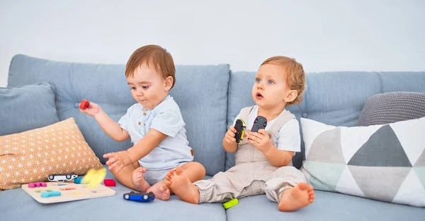 Gyönyörű Kisbabák Ülnek Kanapén Otthon Játszanak Játékaikkal — Stock Fotó
