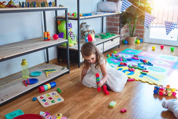 可爱的金发碧眼的幼儿在幼儿园的许多玩具周围玩积木游戏 — 图库照片