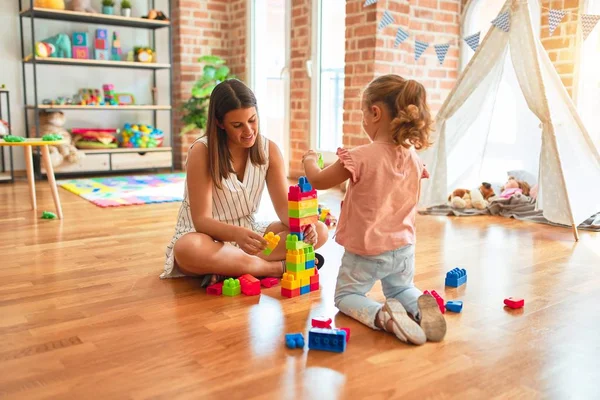 Schöne Lehrerin Und Blondes Kleinkind Bauen Turm Aus Plastikklötzen Kindergarten — Stockfoto