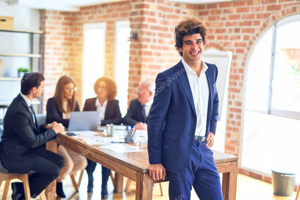 Group of business workers smiling happy and confident working together in a meeting. One of them, standing with smile on face looking at camera at the office.