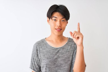 İzole edilmiş beyaz arka plan üzerinde duran gündelik tişört giyen genç Çinli bir adam bir fikir ya da soru işareti ile şaşırdı.