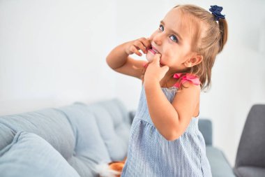 Genç, güzel sarışın kız çocuk anaokulunda oyuncaklarla oyun oynuyor, komik suratlar yapıyor.