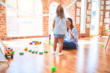 Beyaz kız çocuk, bayan öğretmenle oyun oynayıp öğreniyor. Anne ve kız oyun odasında oyuncaklarla oynuyorlar.