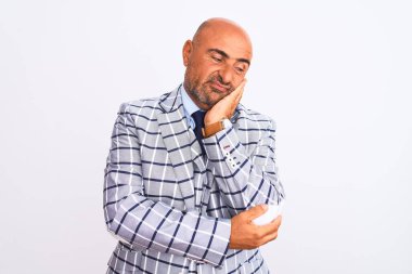 Orta yaşlı iş adamı beyaz arka planda dikilip kollarını kavuşturarak depresyondan sıkılmış ve yorgun gözüktüğünü düşünüyor..