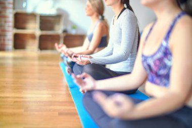 Genç ve güzel bir grup sporcu kadın yoga yapıyor. Spor salonunda nilüfer pozu veriyorum.