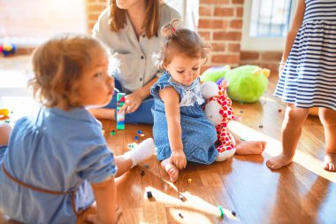 Güzel öğretmen ve bir grup çocuk anaokulunda bir sürü oyuncakla oynuyorlar.