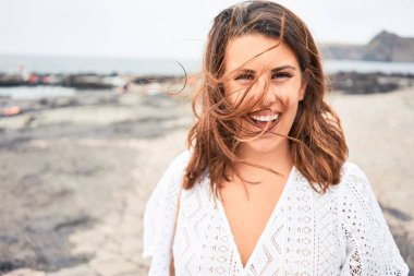 Genç ve güzel bir kadın gülümseyerek Kanarya Adaları 'ndaki siyah kumsalda yaz tatilinin tadını çıkarıyor.