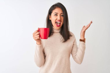Beautiful chinese woman drinking red cup of coffee standing over isolated white background very happy and excited, winner expression celebrating victory screaming with big smile and raised hands