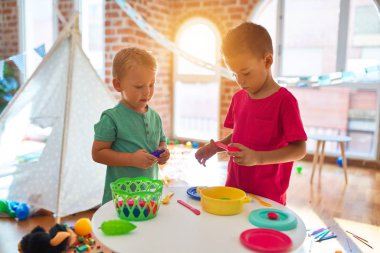 Anaokulunda bir sürü oyuncakla oynayan sevimli çocuklar.