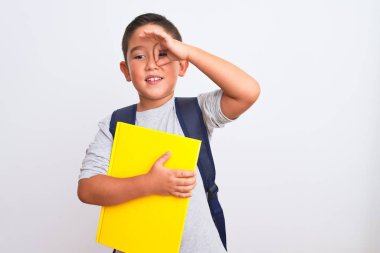 Sırt çantası taşıyan güzel öğrenci gülümseyen yüzüyle izole edilmiş beyaz arka planda kitap tutuyor.