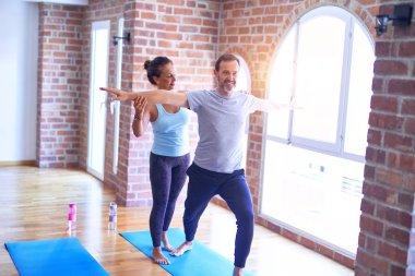 Orta yaşlı güzel sporcu çift mutlu gülümsüyor. Yoga dersinden sonra spor salonunda durup esneme hareketleri yapmak.