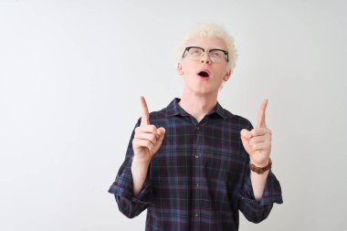 Genç albino sarışın adam, günlük gömlek ve gözlük takıyor, beyaz arka planda şaşkın şaşkın bakıyor, parmaklarıyla işaret ediyor ve kollarını kaldırıyordu..