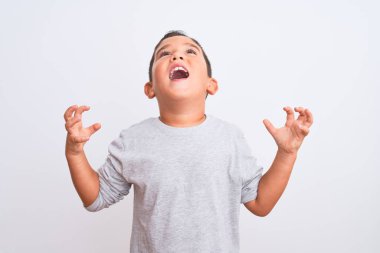 Gri günlük tişört giyen güzel çocuk izole edilmiş beyaz arka plan üzerinde duruyor. Deli gibi bağırıyor ve agresif bir ifadeyle bağırıyor ve kollarını kaldırıyor. Hayal kırıklığı konsepti.