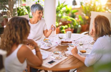 Genç ve güzel bir kız mutlu ve kendinden emin bir şekilde terasta oturmuş bir fincan kahve içiyor.