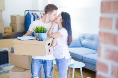 Young beautiful couple sitting on the floor at new home around cardboard boxes celebrating surprised and amazed for success with arms raised and open eyes. Winner concept.
