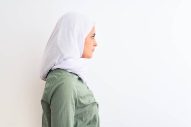 Geleneksel Müslüman tesettüre bürünmüş genç, güzel bir Arap kadın. Tarafsız bir arkaplan arıyor, rahat profil pozu veriyor, kendine güvenen bir gülümsemeyle..