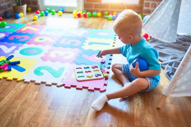 Genç beyaz bir çocuk anaokulunda numaralarla oynuyor. Anaokulu çocuğu oyun odasında matematik yapıyor..